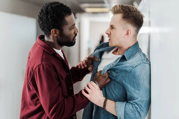 Two multiethnic students fighting in corridor in college — Stock Photo