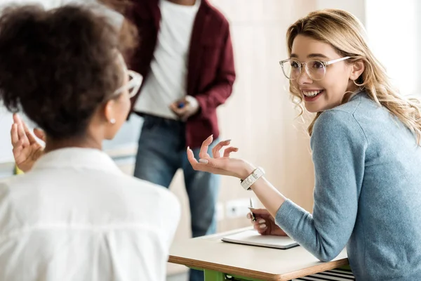 Smiling multiethnic students looking at each other talking in university — Stock Photo