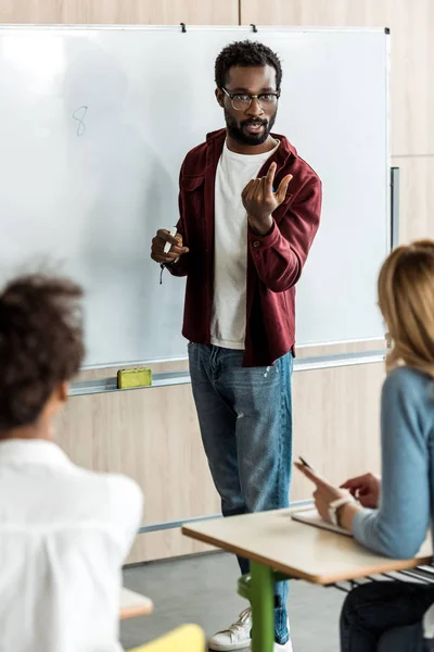 Étudiant afro-américain dans des lunettes debout près du tableau noir — Photo de stock