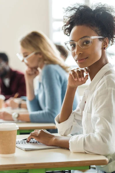 Studente afroamericano seduto alla scrivania con taccuino e tazza di caffè — Foto stock