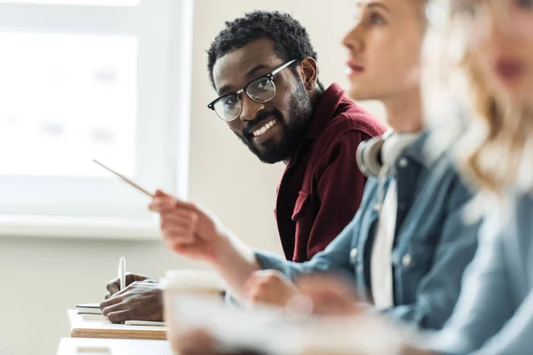 Estudiante afroamericano sonriente en gafas mirando a la cámara — Stock Photo