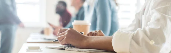 Panoramic shot of students at desks in university — Stock Photo