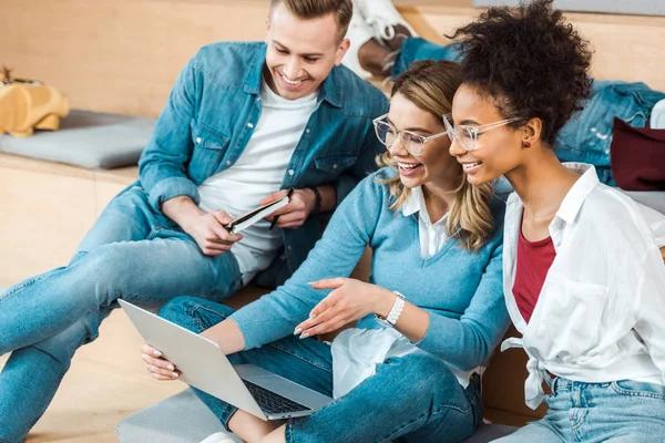 Smiling multicultural students using laptop in lecture hall — Stock Photo