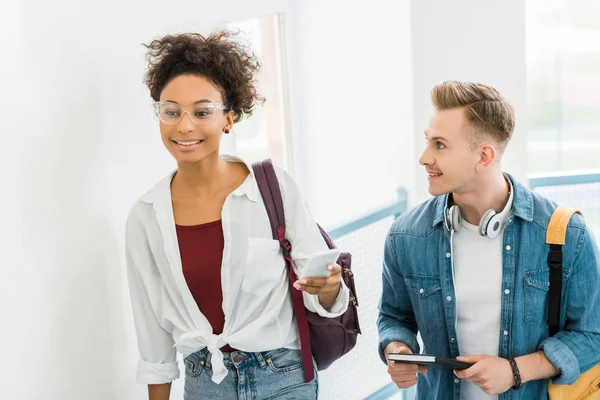 Zwei multikulturelle Studenten mit Notebook und Smartphone im College — Stockfoto