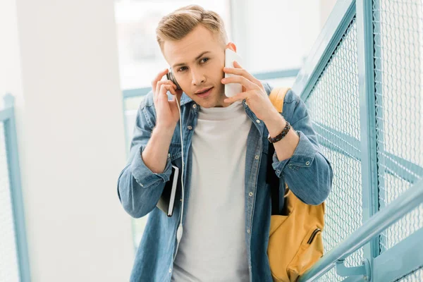 Student mit Kopfhörer und Rucksack spricht auf Smartphone — Stockfoto