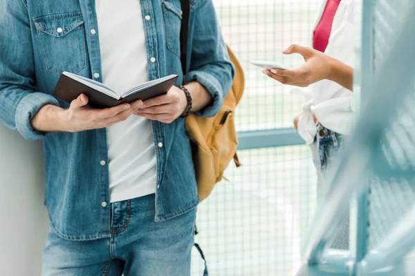Partial view of two students with notebook and smartphone — Stock Photo