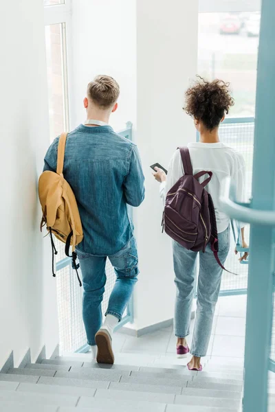 Visão traseira de dois estudantes internacionais com mochilas — Fotografia de Stock