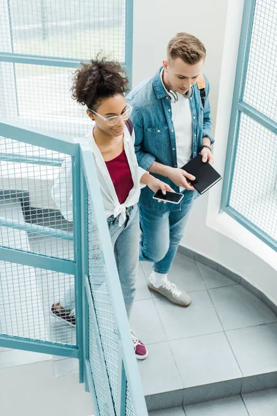 Vue aérienne de deux étudiants avec ordinateur portable et smartphone debout sur les escaliers — Photo de stock