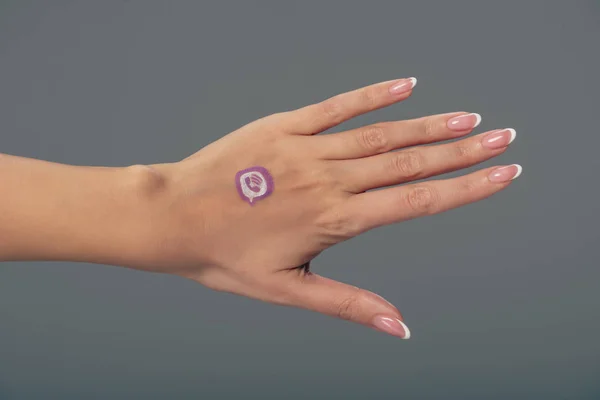 Vista recortada de la mano femenina con logo viber aislado en gris - foto de stock