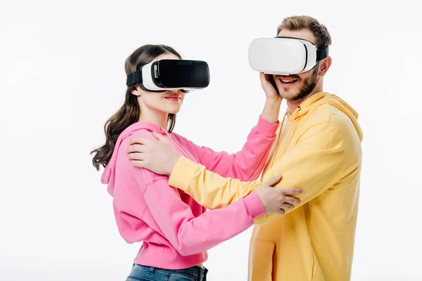 Young man and woman embracing while using virtual reality headsets isolated on white — Stock Photo