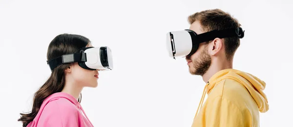 Plano panorámico de hombre y mujer jóvenes en auriculares de realidad virtual aislados en blanco - foto de stock