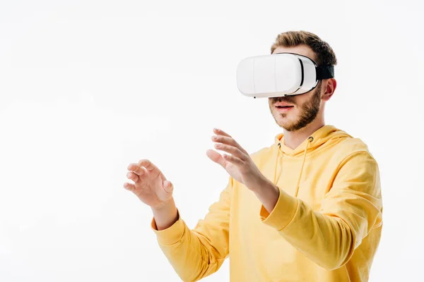 Joven con capucha amarilla usando auriculares de realidad virtual aislados en blanco - foto de stock