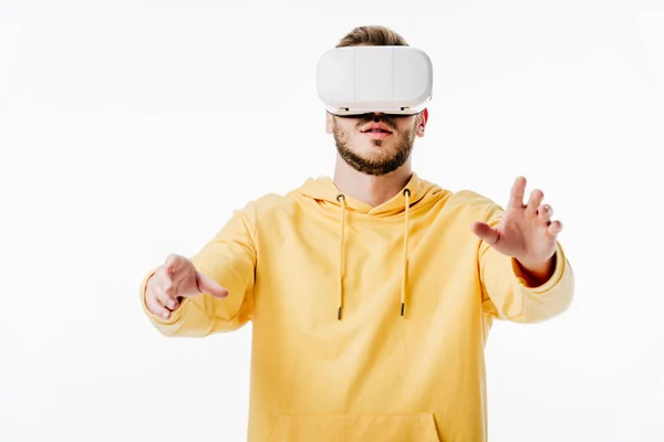 Vista frontal del joven con capucha amarilla usando auriculares de realidad virtual aislados en blanco - foto de stock