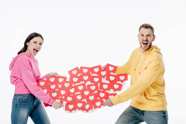 Young couple quarreling while holding red paper cards with hearts symbols isolated on white — Stock Photo