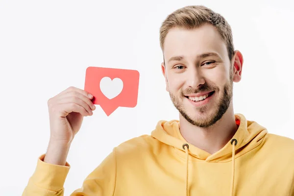 Красивый веселый мужчина держит красную бумажную карточку с символом сердца и смотрит на камеру, изолированную на белом — стоковое фото