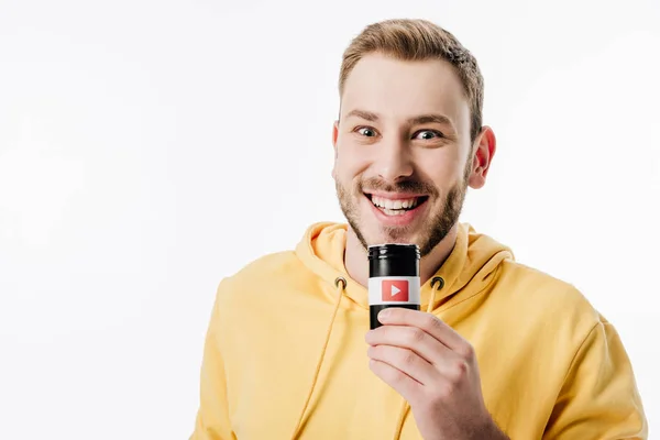 Excited young man in yellow hoodie holding container with youtube logo and looking at camera isolated on white — Stock Photo