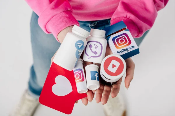 Overhead view of girl holding containers with social media logos and red paper cut card with heart symbol on grey background — Stock Photo