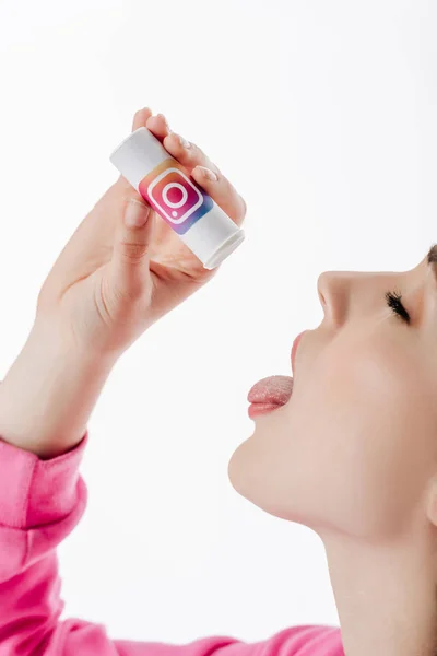 Mujer joven con los ojos cerrados imitando las píldoras de deglución del envase con el logotipo de instagram aislado en blanco - foto de stock