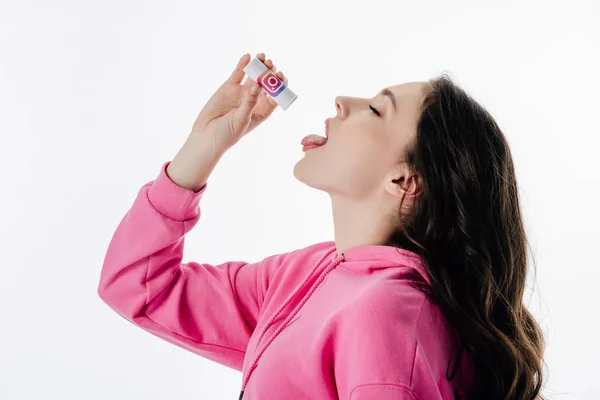 Pretty girl with closed eyes imitating using pills from container with instagram logo isolated on white — Stock Photo