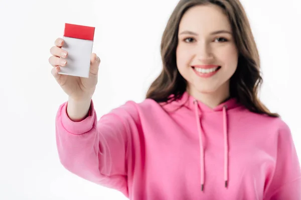 Selective focus of smiling young girl holding cigarette pack and looking at camera isolated on white — Stock Photo