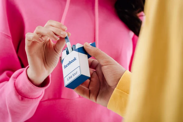 Cropped view of man and woman holding cigarette pack with facebook logo — Stock Photo