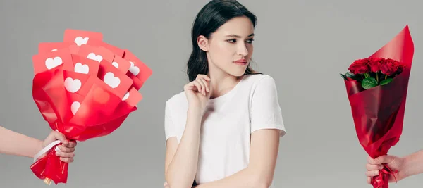 Partial view of male hands with bouquet of roses and bouquet made of red paper cut cards near attractive young woman isolated on grey — Stock Photo