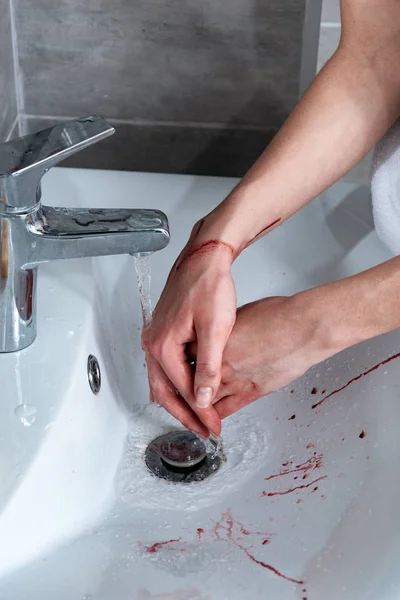 Vista parcial de la mujer lavándose las manos sangrantes en el baño - foto de stock