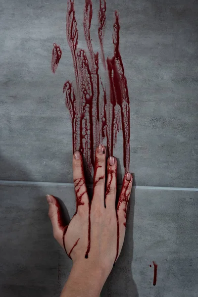 Bleeding hand and blood print on grey wall — Stock Photo