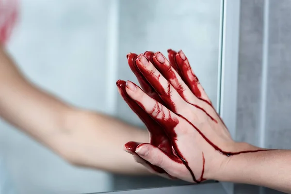 Partial view of woman with bleeding hand touching mirror in bathroom — Stock Photo