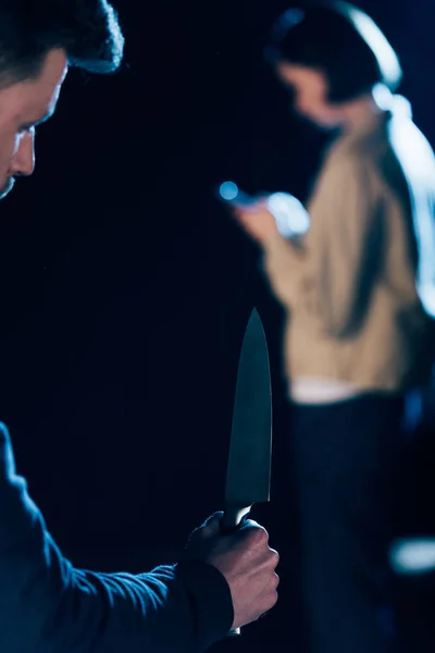 Cropped view of killer holding knife near woman on black — Stock Photo