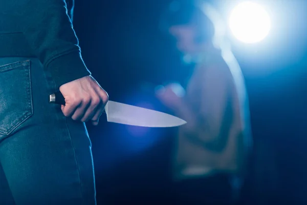 Cropped view of killer holding knife near woman on black — Stock Photo