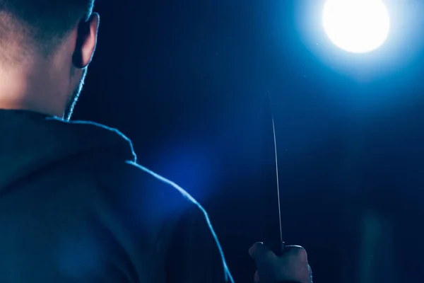 Cropped view of killer holding knife on black — Stock Photo