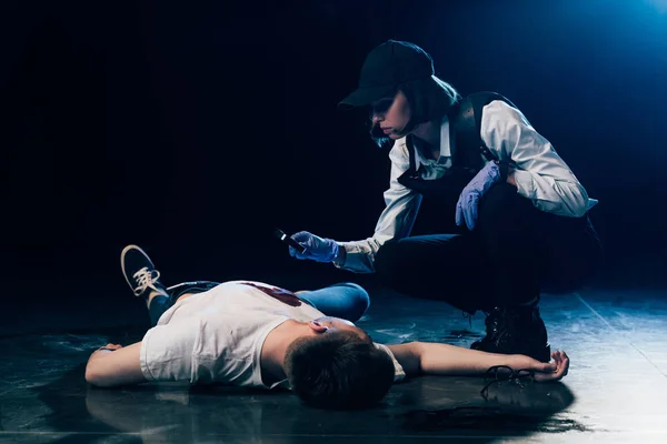 Investigator looking at wound on corpse with magnifying glass at crime scene — Stock Photo