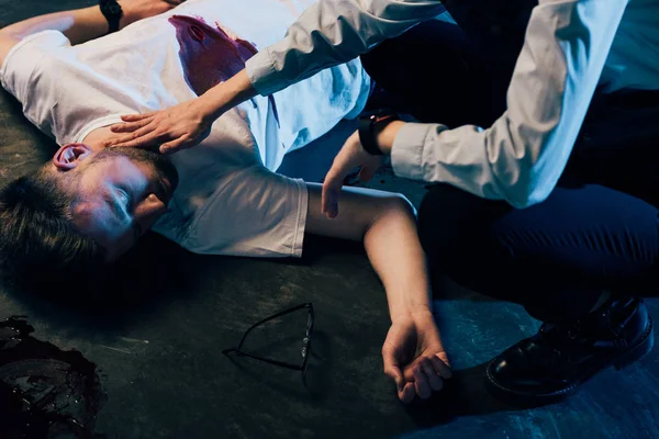 Cropped view of investigator checking pulse on dead man at crime scene — Stock Photo