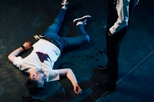 Cropped view of investigator in uniform standing near corpse at crime scene — Stock Photo