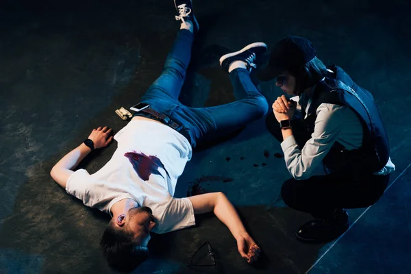 Overhead view of investigator sitting near cadaver at crime scene — Stock Photo