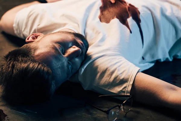 Dead man with blood on t-shirt on floor at crime scene — Stock Photo