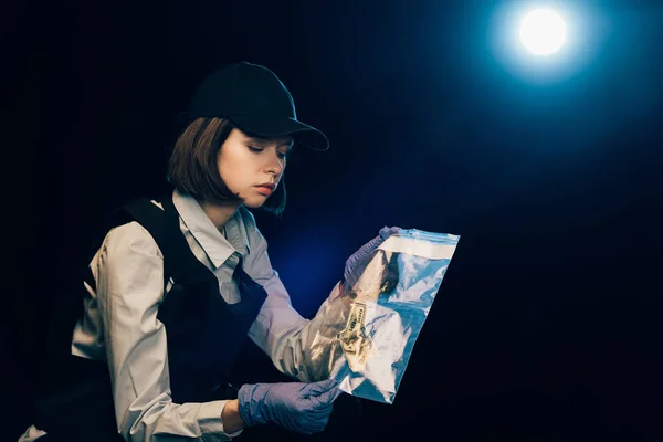 Investigator in rubber gloves holding ziploc bag with dollar banknote at crime scene — Stock Photo