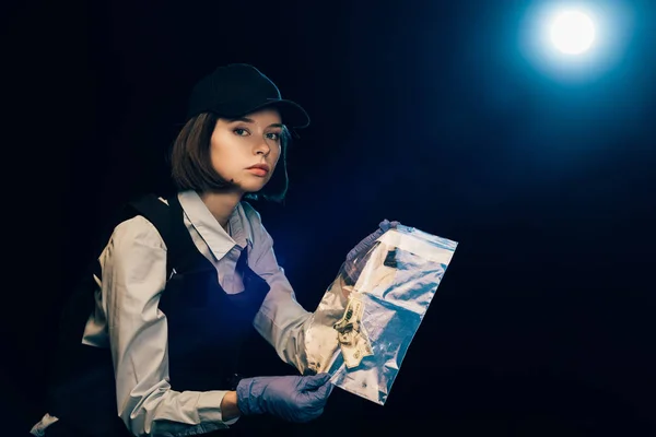 Investigator in rubber gloves holding ziploc bag with dollar banknote at crime scene — Stock Photo