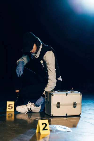 Investigator in uniform holding shoe at crime scene — Stock Photo