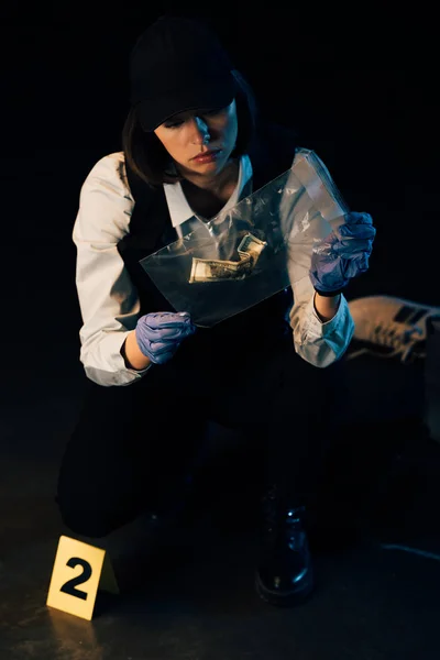 Investigator in rubber gloves holding ziploc bag with dollar banknote at crime scene — Stock Photo