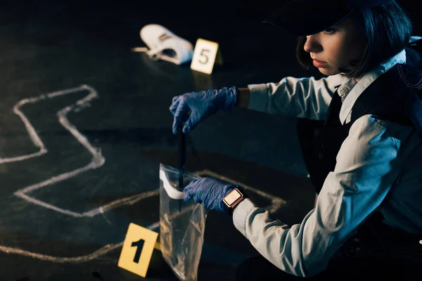 Investigador en uniforme recogiendo evidencias en la escena del crimen - foto de stock