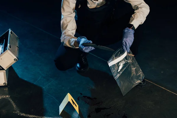 Vista recortada del investigador poniendo cuchillo en la bolsa ziploc en la escena del crimen - foto de stock