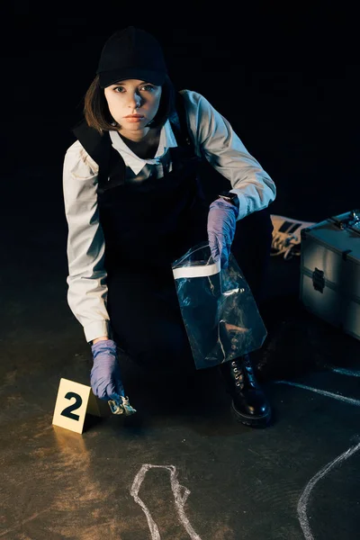 Serious investigator holding dollar banknote and ziploc bag at crime scene — Stock Photo