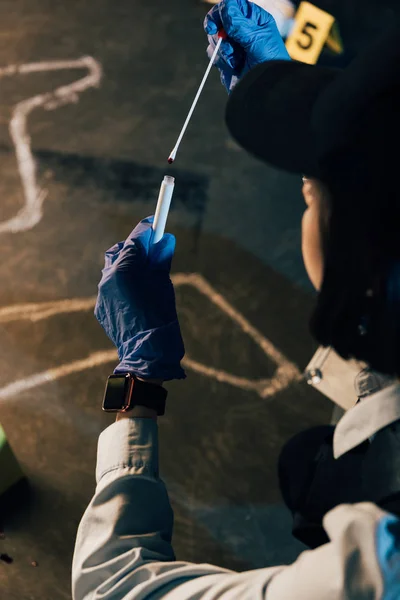 Vue recadrée de l'enquêteur portant des gants de caoutchouc tenant un écouvillon et un tube à essai sur les lieux du crime — Photo de stock