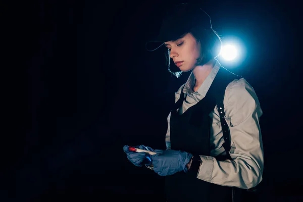 Investigator in rubber gloves holding test tube at crime scene — Stock Photo