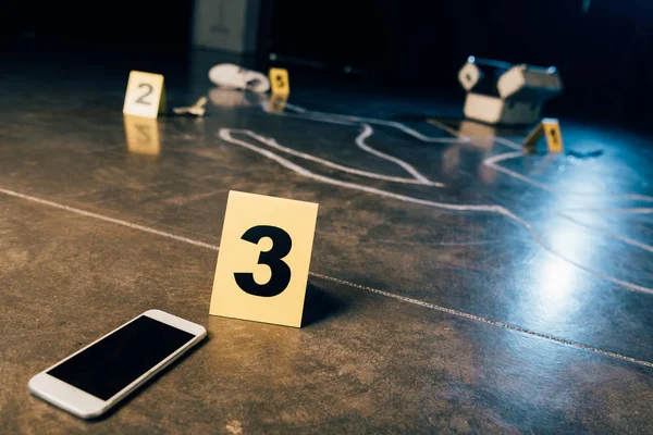 Giz contorno, smartphone com tela em branco e marcadores de evidência na cena do crime — Fotografia de Stock