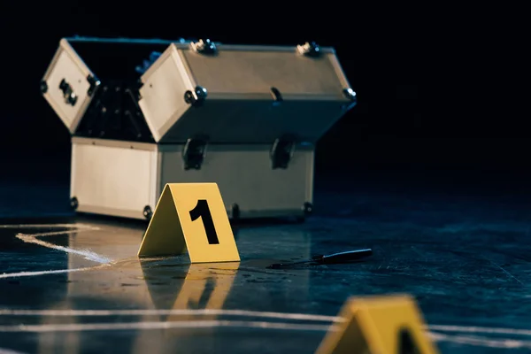 Selective focus of knife, investigation kit, chalk outline and evidence markers at crime scene — Stock Photo