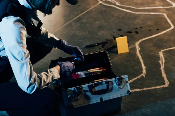 Vue recadrée de l'enquêteur dans des gants de caoutchouc avec trousse d'enquête sur les lieux du crime — Photo de stock