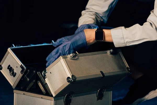 Vista recortada del investigador en guantes de goma con kit de investigación en la escena del crimen - foto de stock